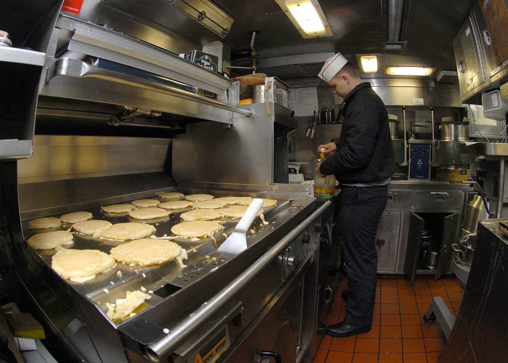 un chef que cocina panqueques en una plancha teppanyaki