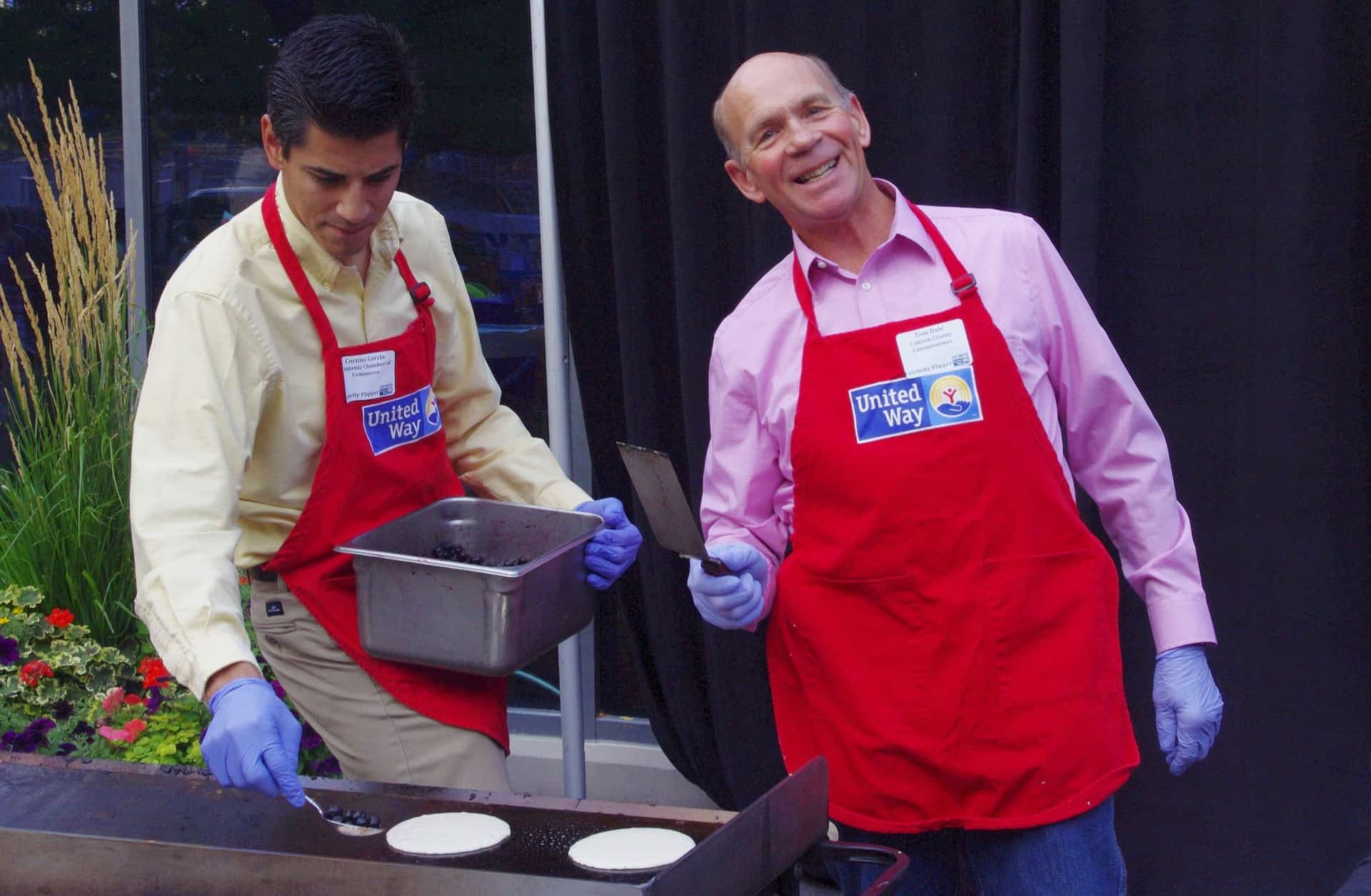 two men is making a blueberry pancake with spatula