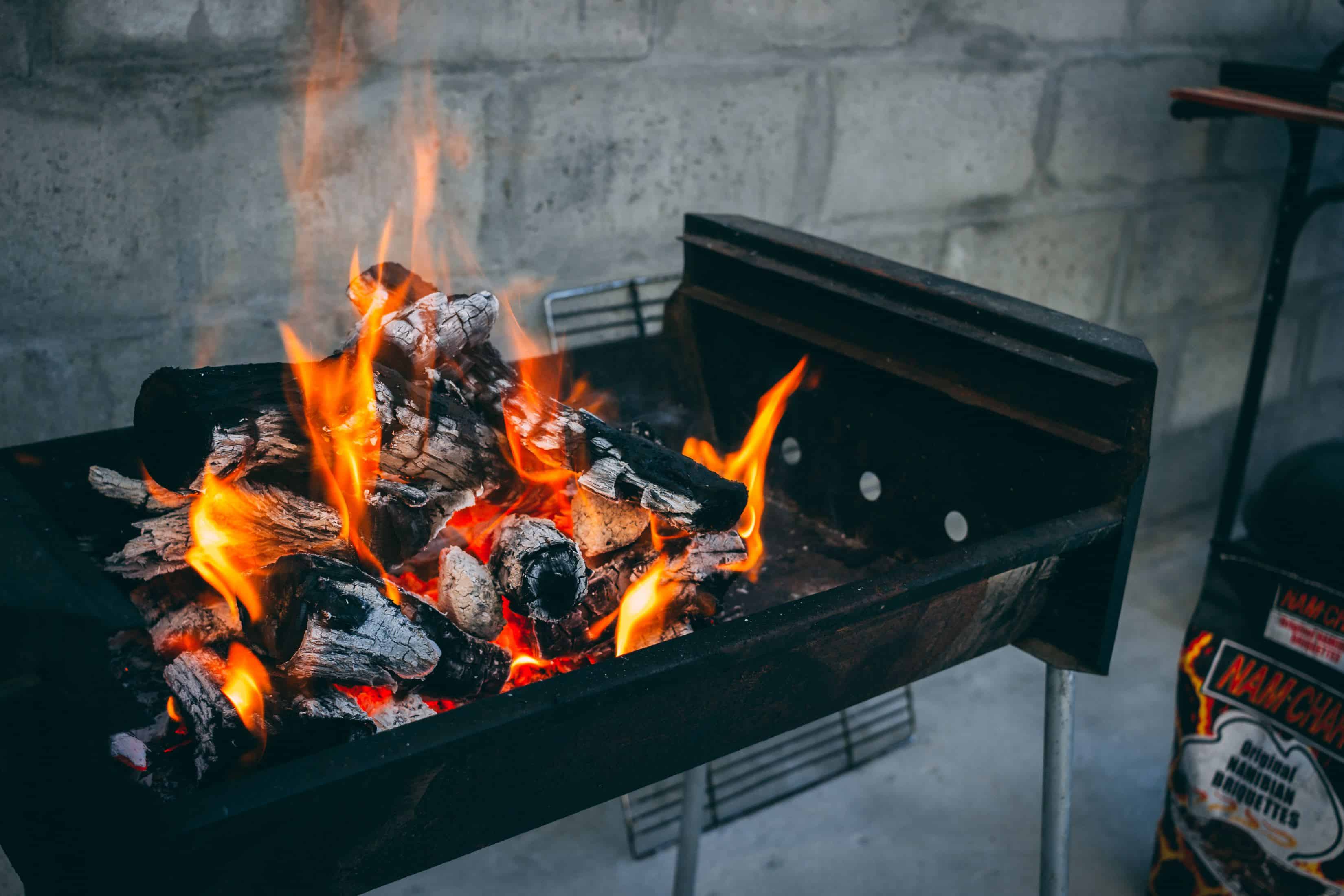 vlammende houtskool op zwarte grill