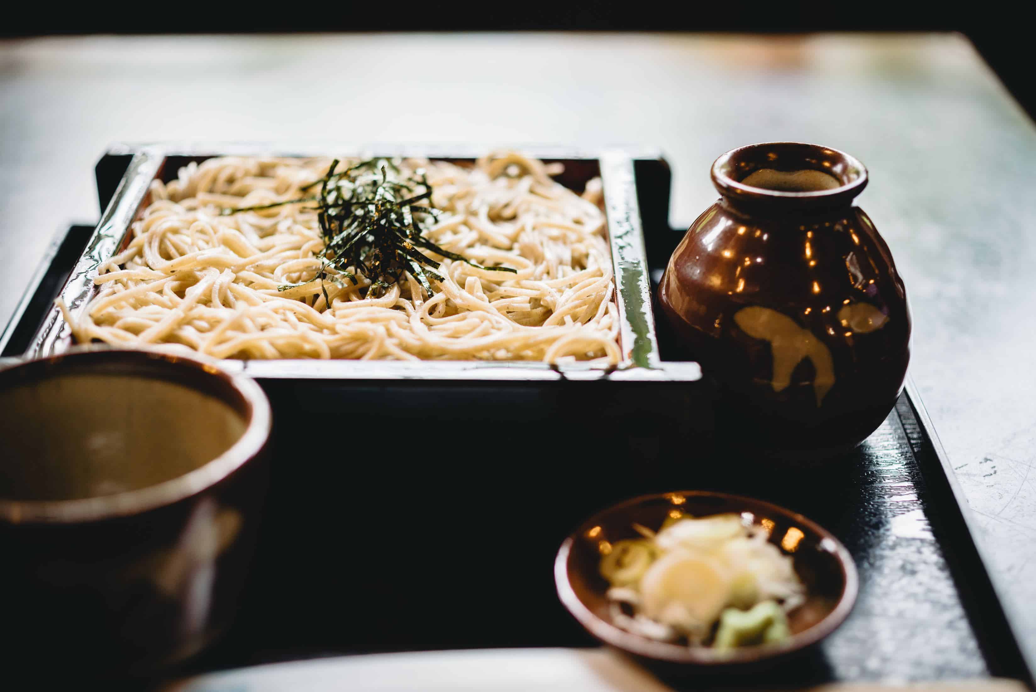 macarrão branco em prato de madeira preto com macarrão soba