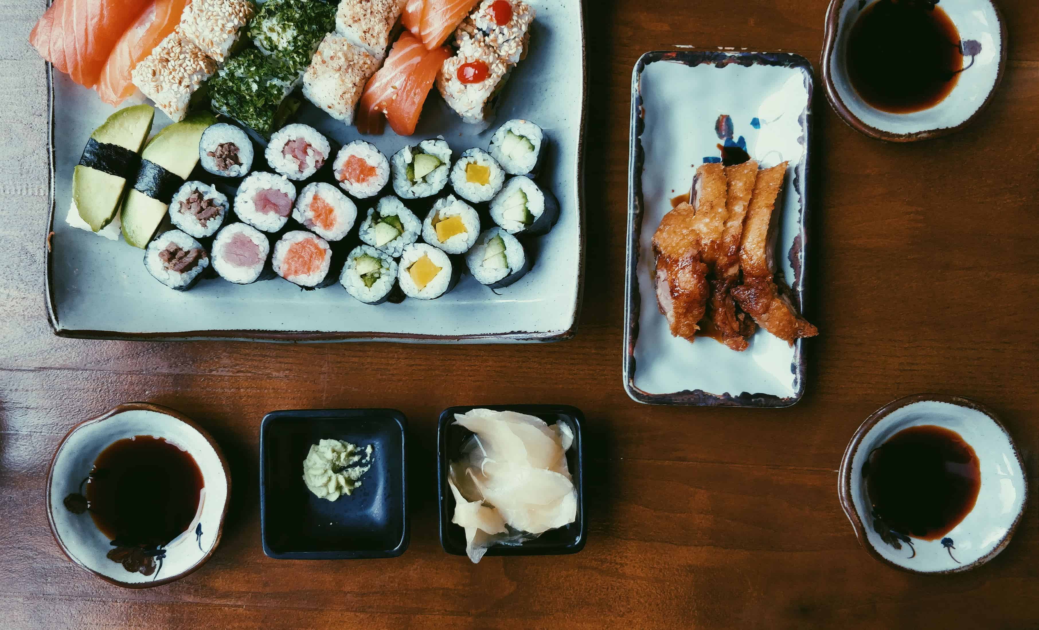 prato com bastante sushi e uma tigela de molho preto