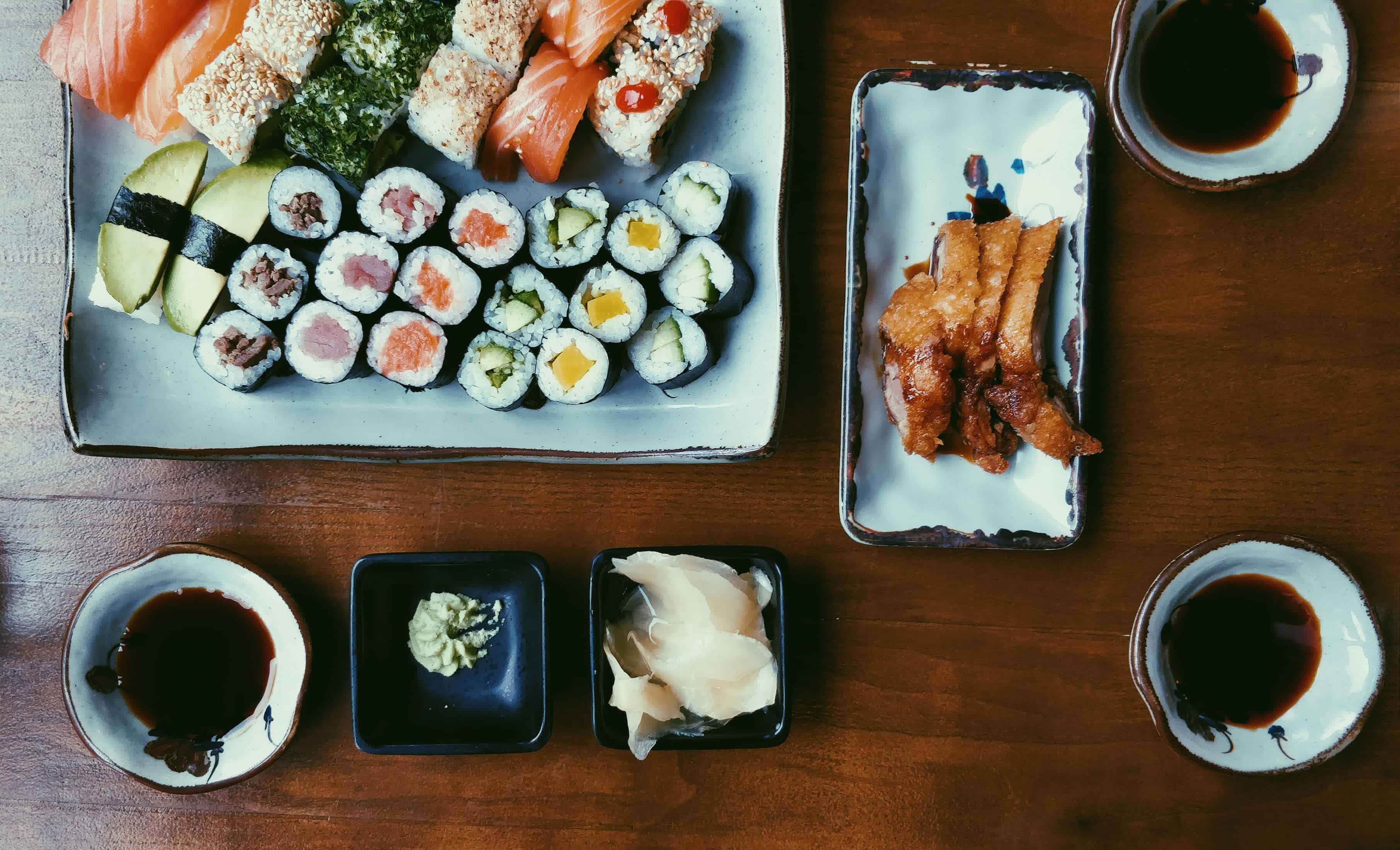 bord met veel sushi en een paar kom zwarte saus