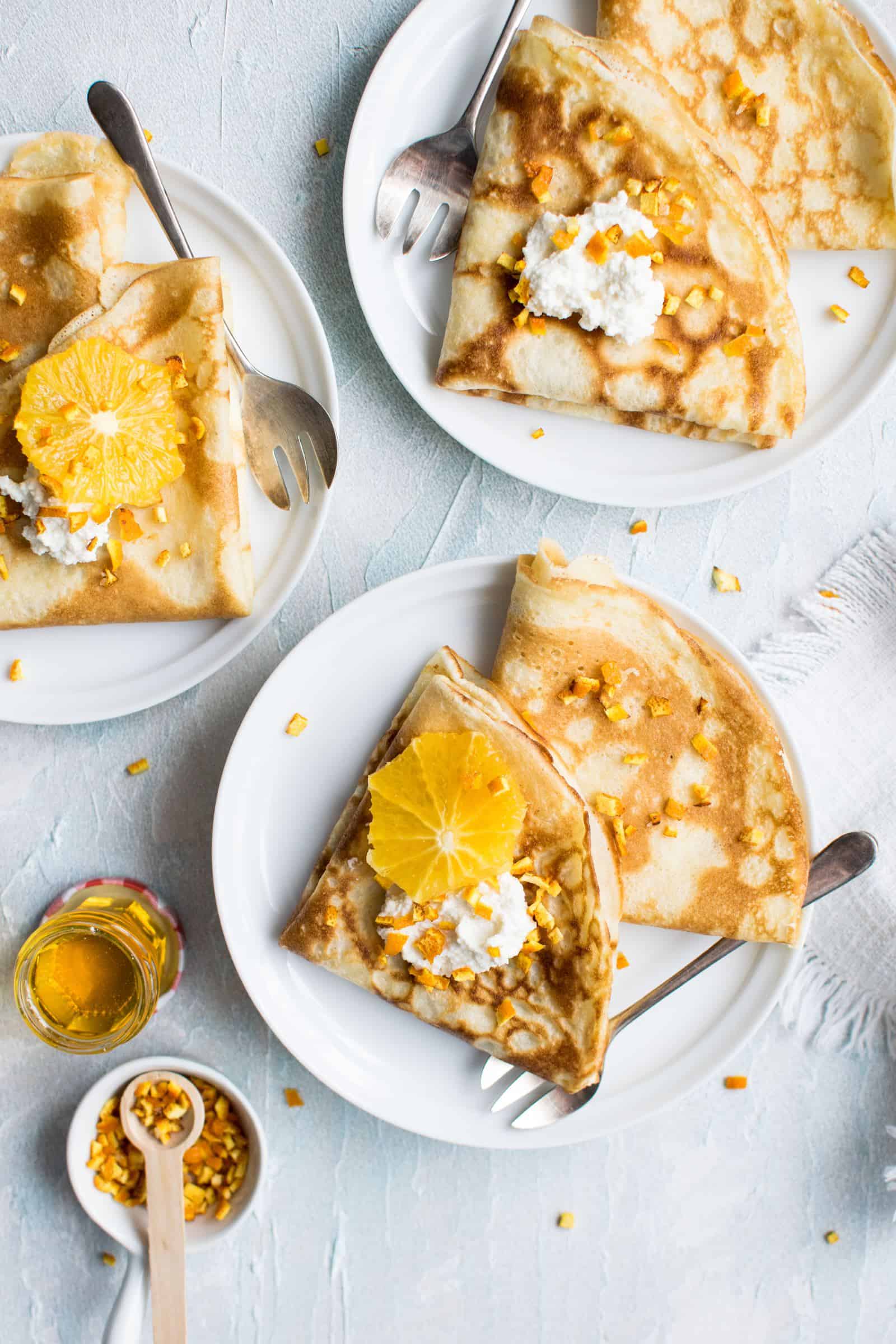 quelques assiettes de crêpes avec des oranges et du miel comme garniture