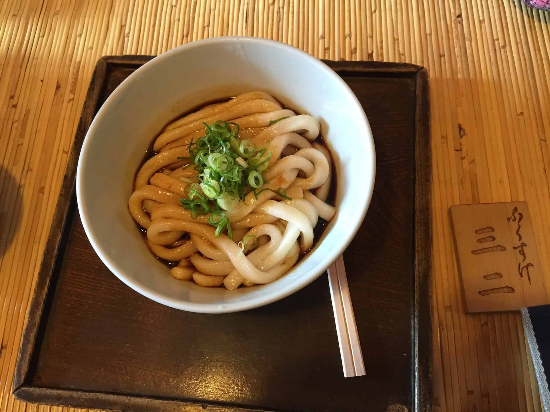 un bol d'udon sur un plateau noir