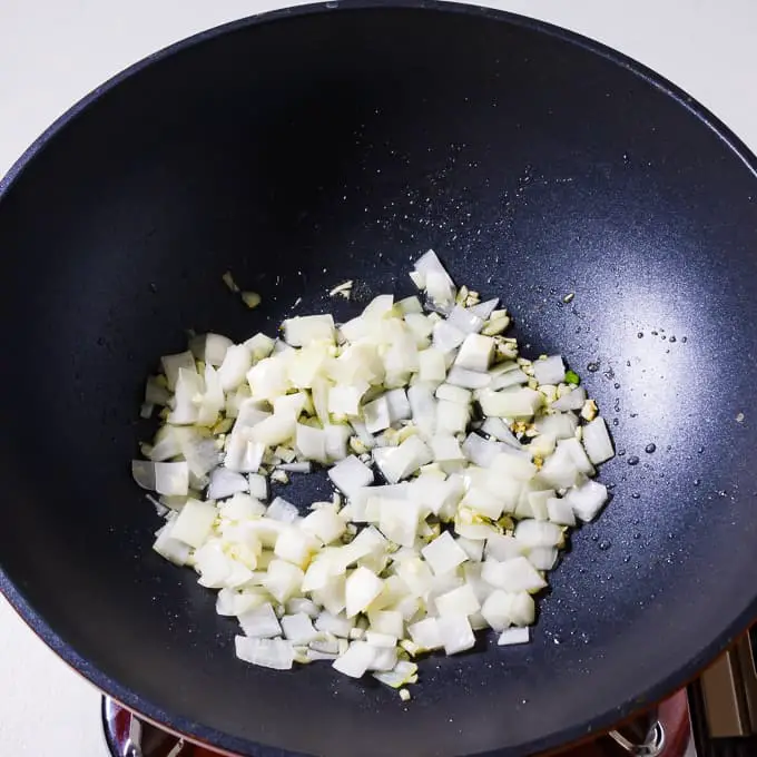 ポークメニュードにんにくと玉ねぎを中華鍋で炒める