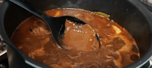Use uma concha para permitir que o pó de curry dourado se dissolva