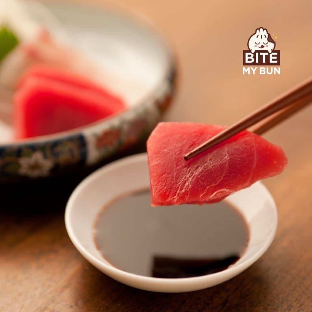 Tuna sashimi tingens cum chopsticks in SOY liquamine