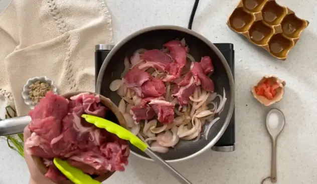 Gyudon pievieno pannai liellopu gaļu ar sautētiem sīpoliem