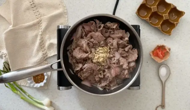 Gyudon adicionando gengibre e sal à carne fervendo