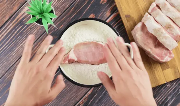 把每一塊豬排都放在麵粉裡，兩面都蓋上。