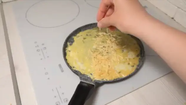 agregue 2.5 cucharadas de queso rallado a un lado de la tortilla