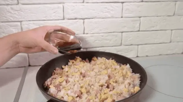 在平底鍋邊緣淋上醬油，然後將米飯翻炒以確保它被包裹