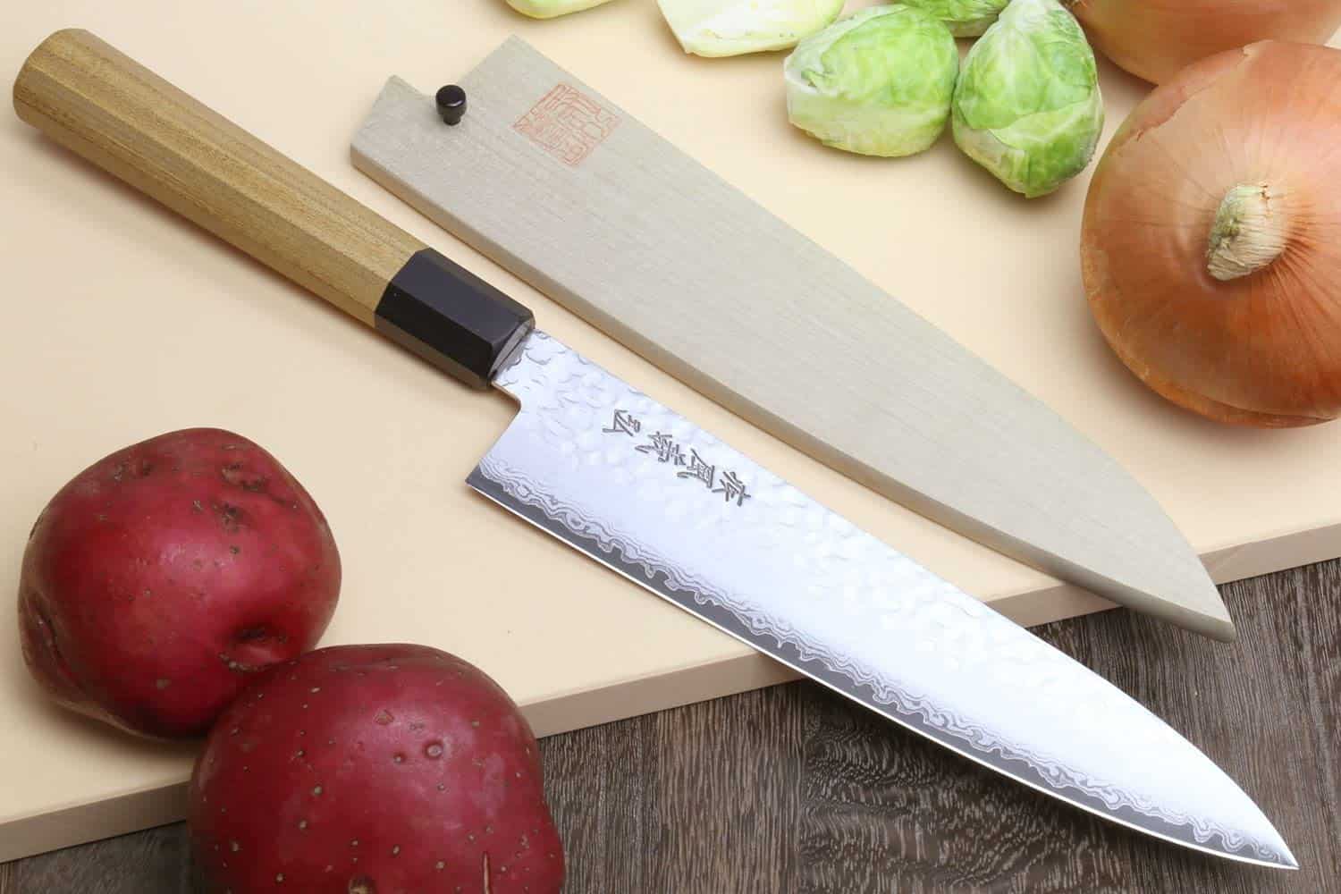 El mejor cuchillo gyuto con funda y lo mejor para chefs: Yoshihiro VG-10 46 capas Damasco martillado en la mesa