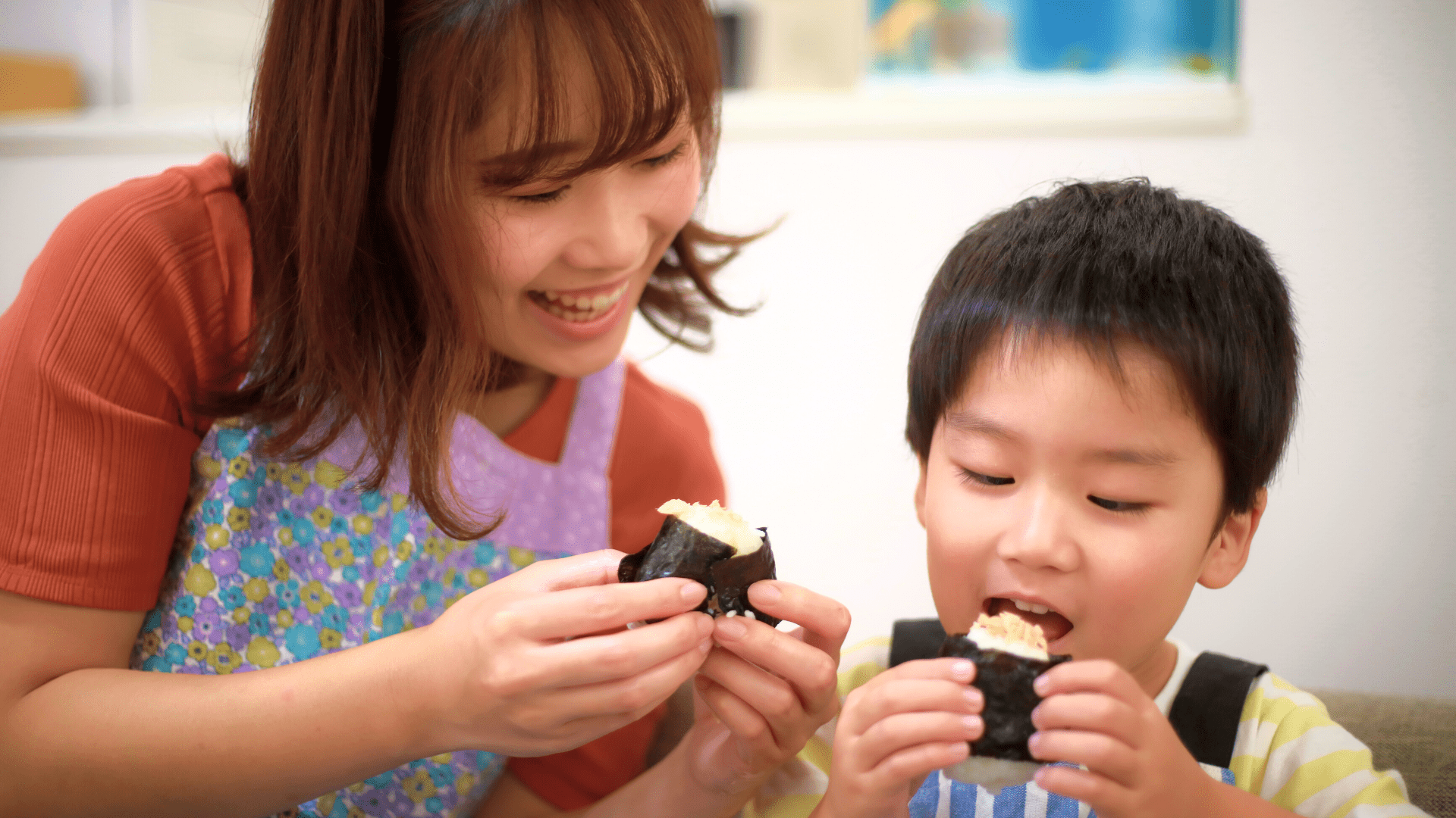 mamma e figlio mangiano insieme un triangolo onigiri