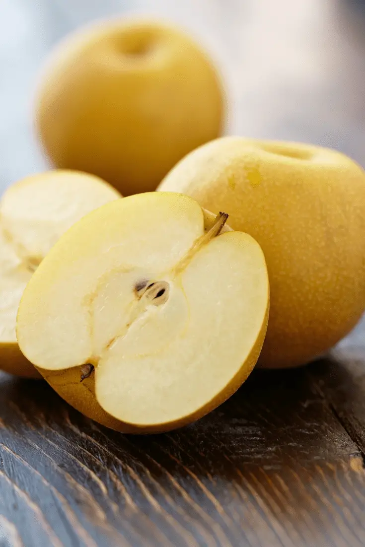 Asian pears on a table, with one sliced in half