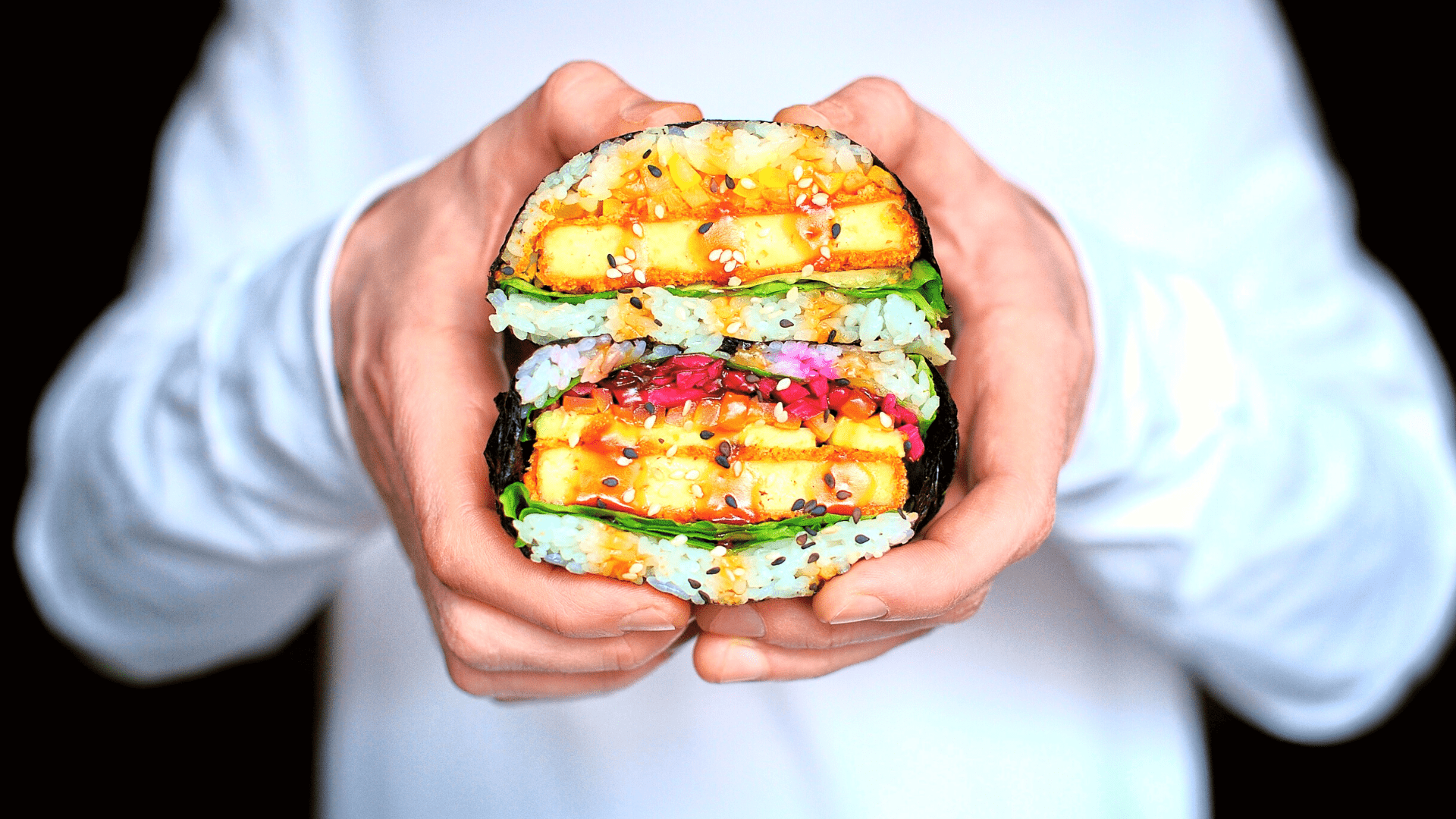 person holding 2 onigirazu sushi sandwich halves on top of each other