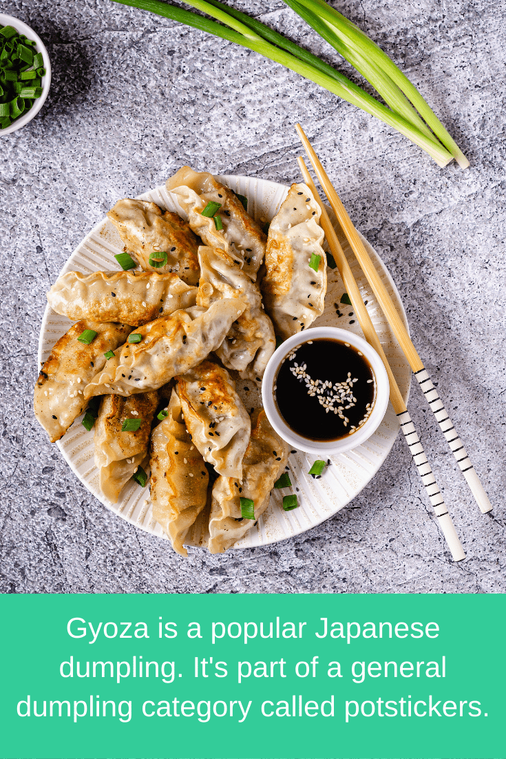 gyoza on a plate with soy sauce, chopsticks, and green onion