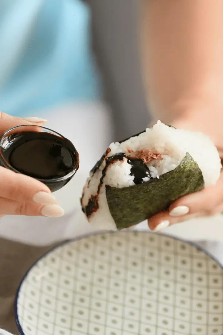 person holding omusubi and soy sauce