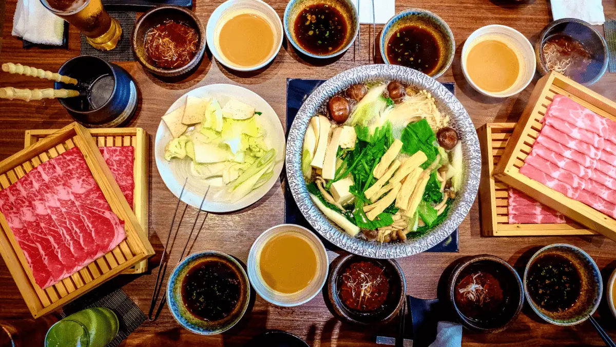 bord med sukuyaki-ingredienser med warishita och andra såser