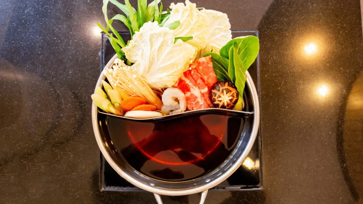 une fondue avec de la viande et des légumes d'un côté et de la sauce warishita sukiyaki de l'autre