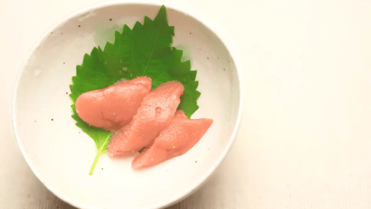 3 pieces of tarako on a white place and leaf garnish