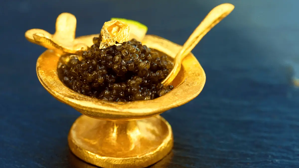 caviar bowfin mewn cwpan aur gyda naddion aur ar ei ben