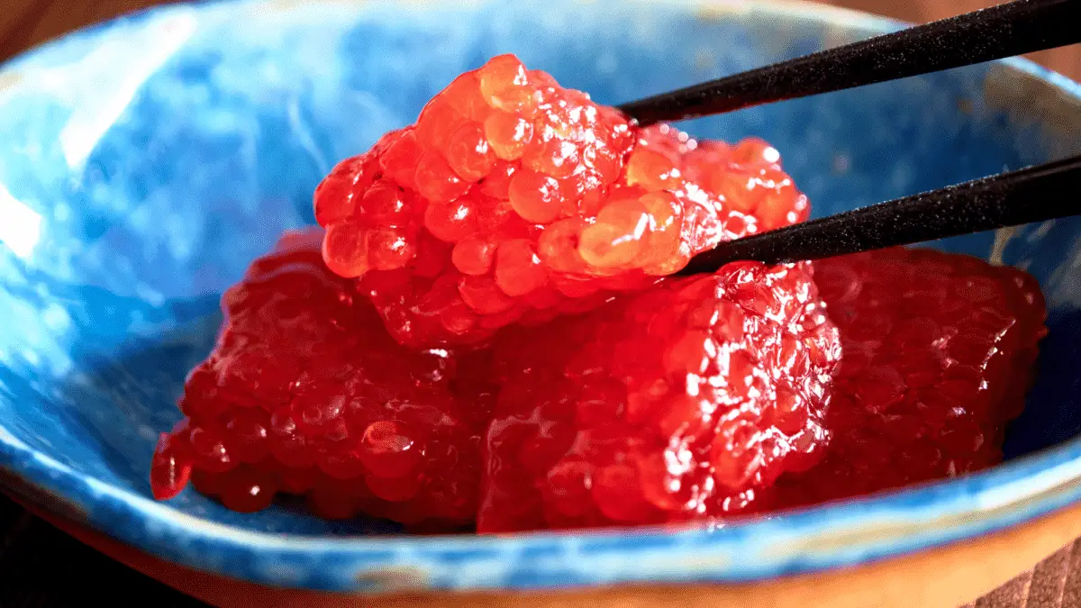 black chopsticks picking up sujiko from a blue plate