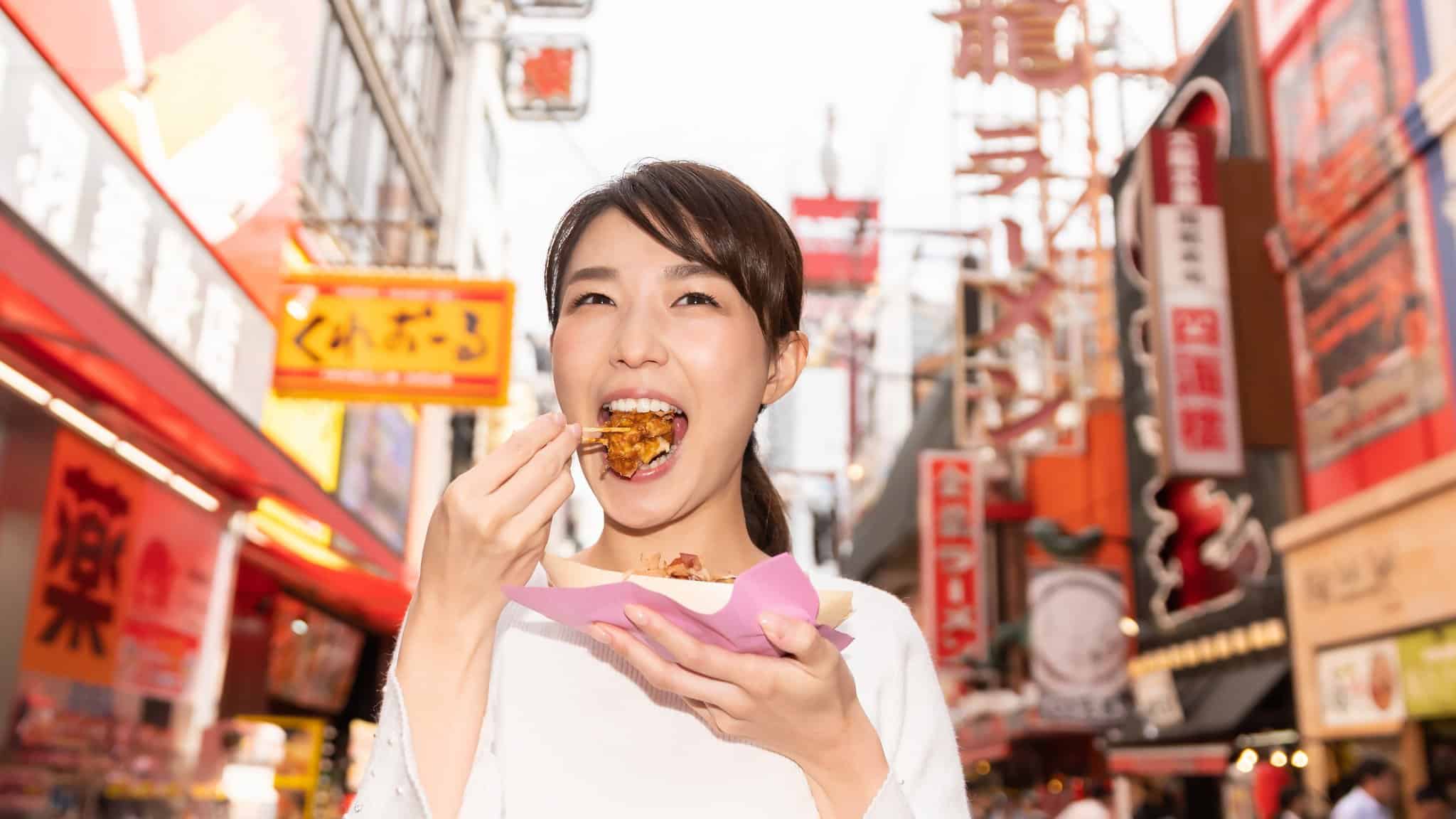 Mujer comiendo takoyaki con un palillo